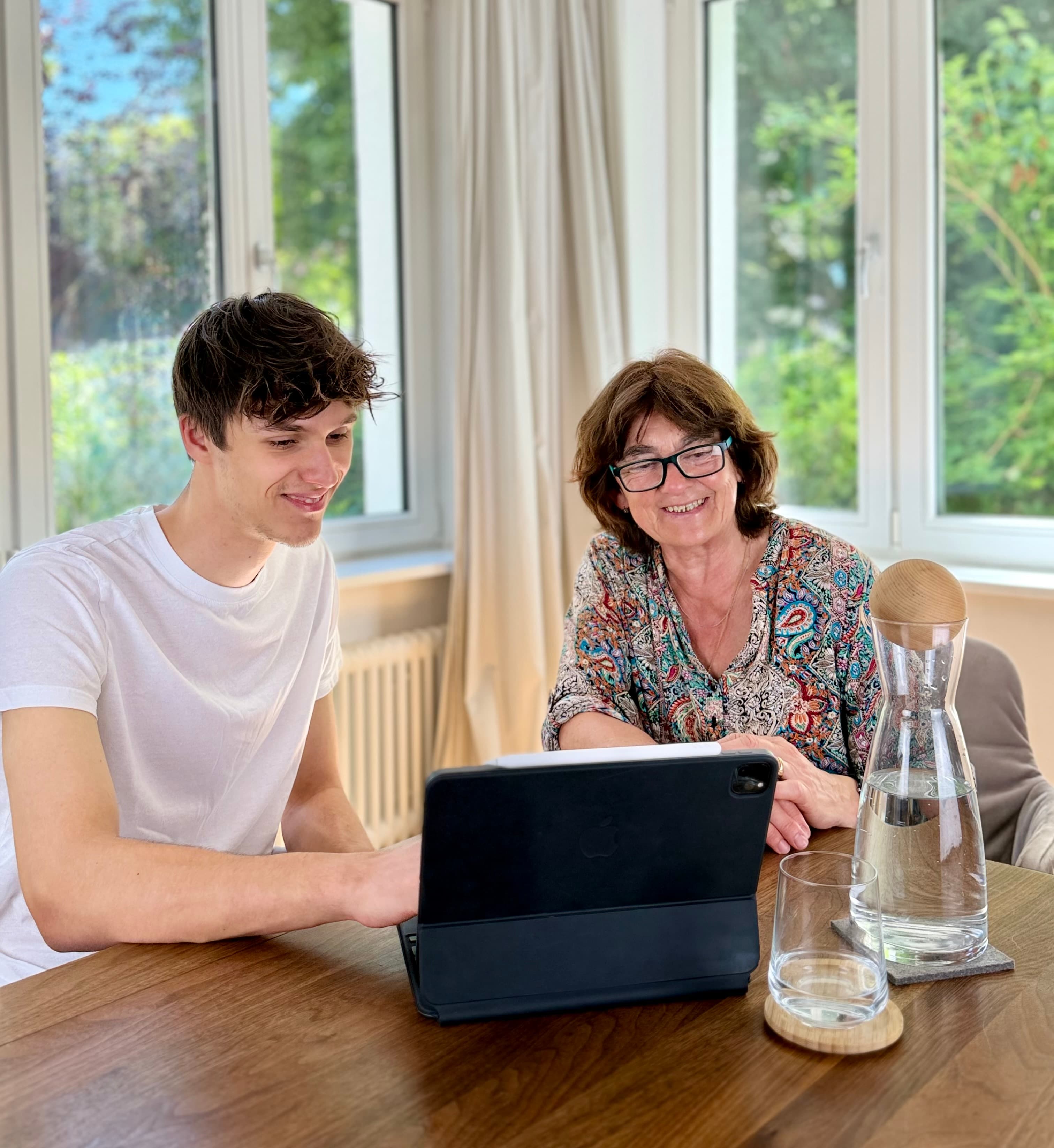 Zwei Menschen verschiedener Generationen schauen gemeinsam auf einen Laptop.